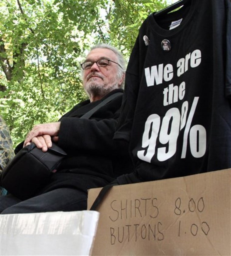 Walter Lichtenberg sits on a park bench selling shirts and buttons at the Occupy Portland camp in downtown Portland, Ore. Enterprising silk-screeners, merchandise hucksters and others are expected to join the movement seeking to profit from the nationwide Occupy movements. 
